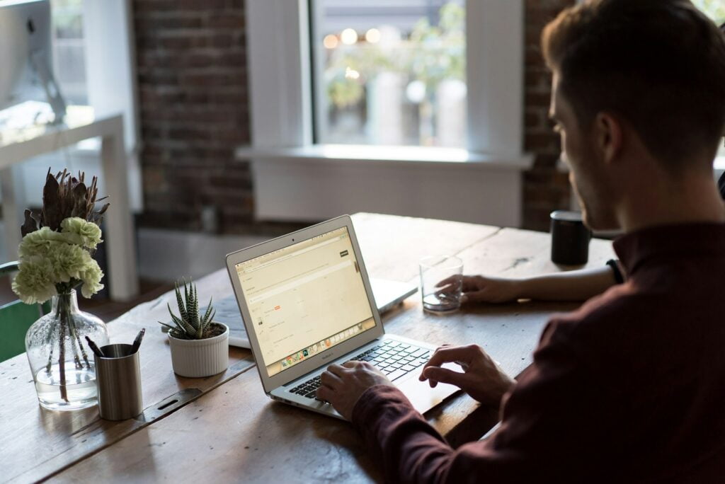 man operating laptop on top of table--