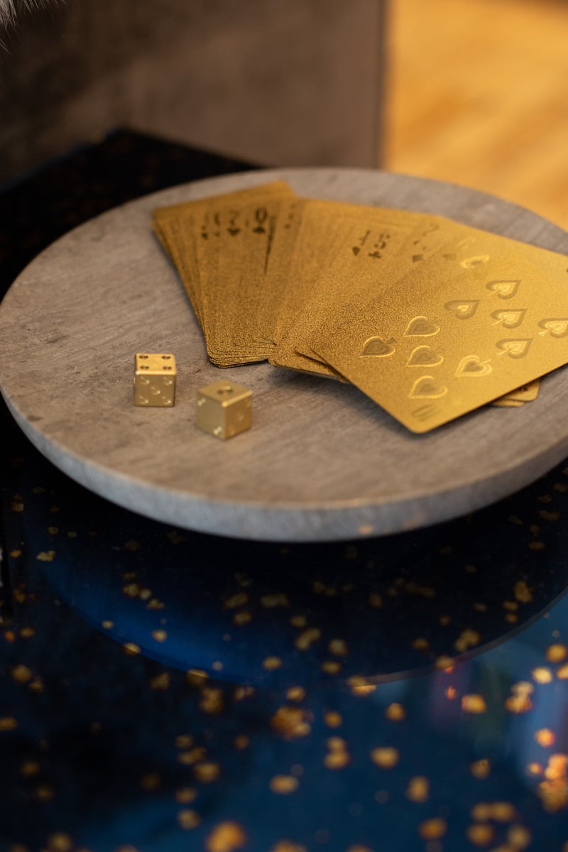 gold cards and two dices on round wooden platform-Exploring the Historical Significance of Gold